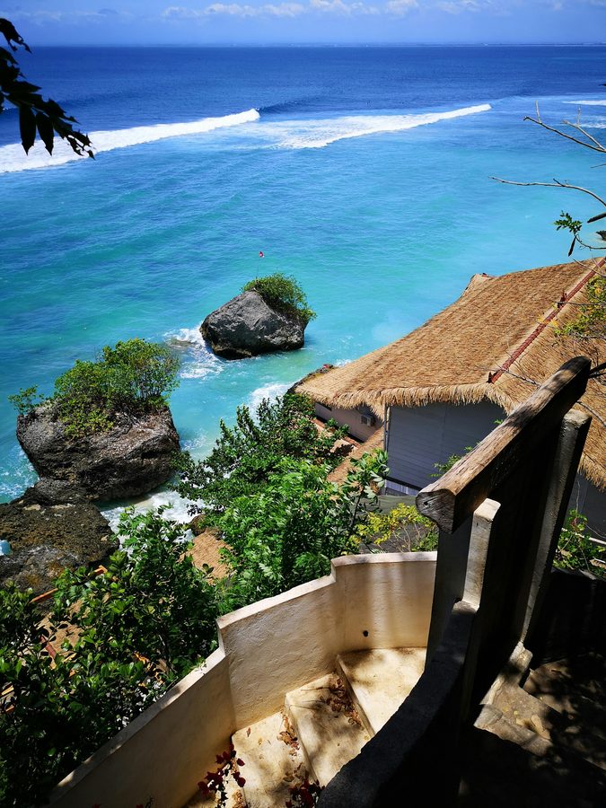 Uluwatu cliff cove with turquoise surf and thatched villa