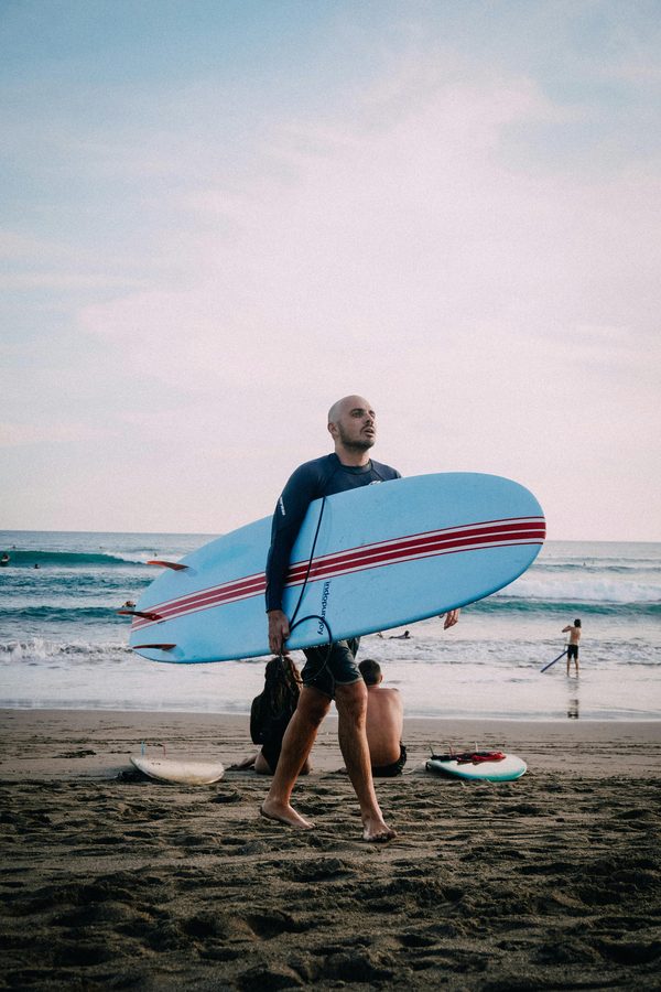 Surfer walking off a Bali beach with his board